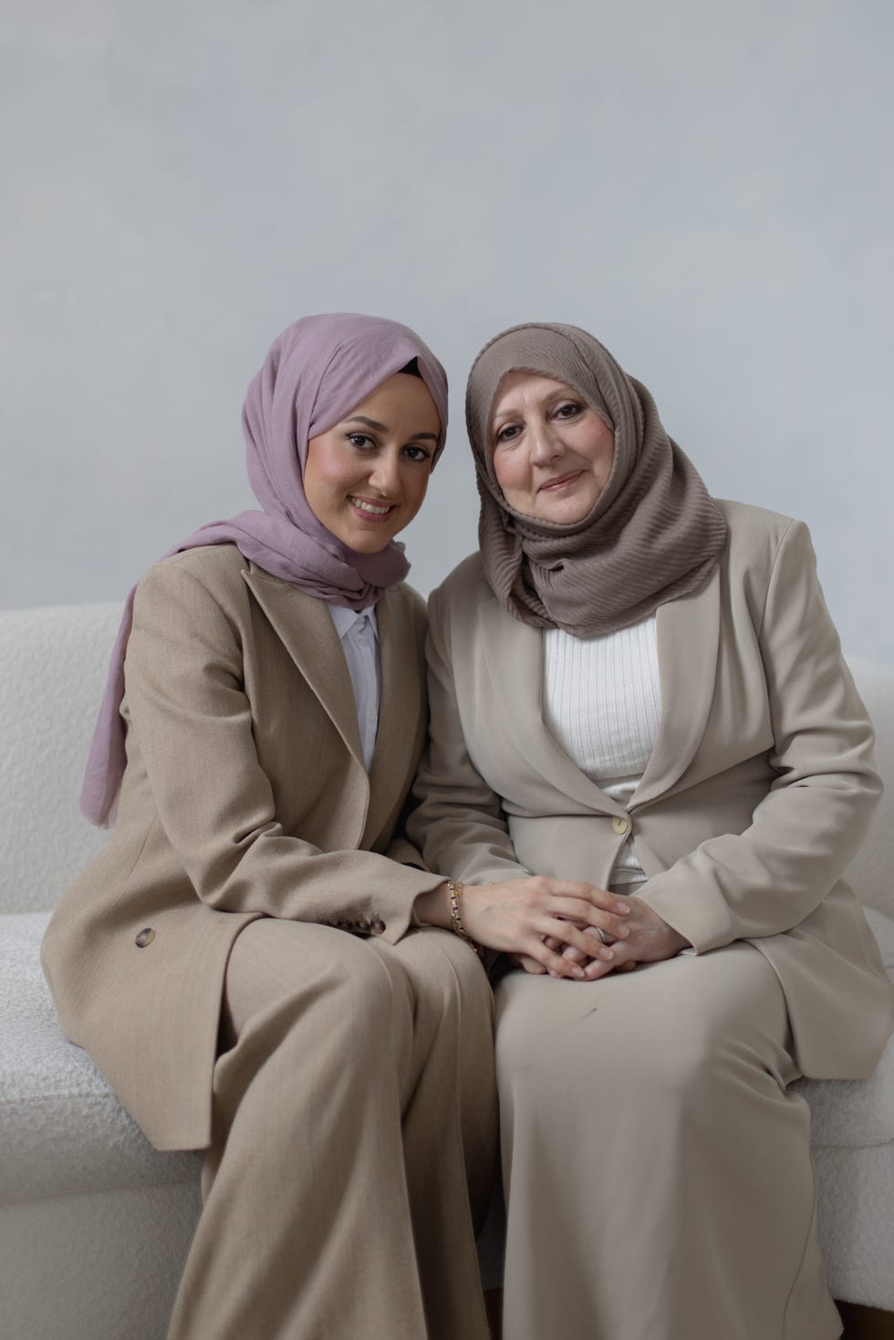 two women in professional attire sitting closely together
