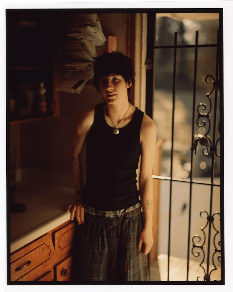 Kaleb stands in a doorway inside a home, lit by natural light.