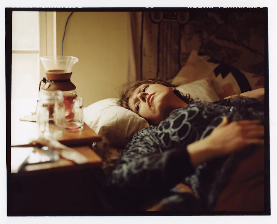 Bailey lies on a bed near a window with soft natural light.