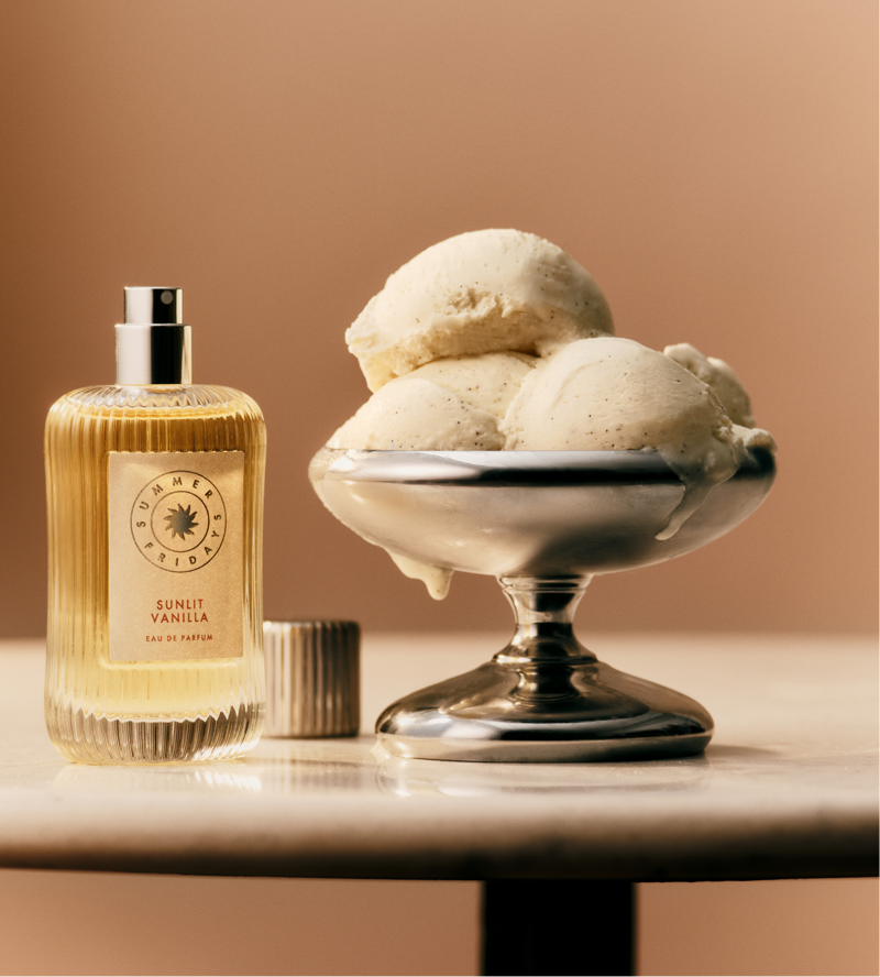 A bottle of Sunlit Vanilla eau de parfum next to a silver tray of vanilla ice cream.