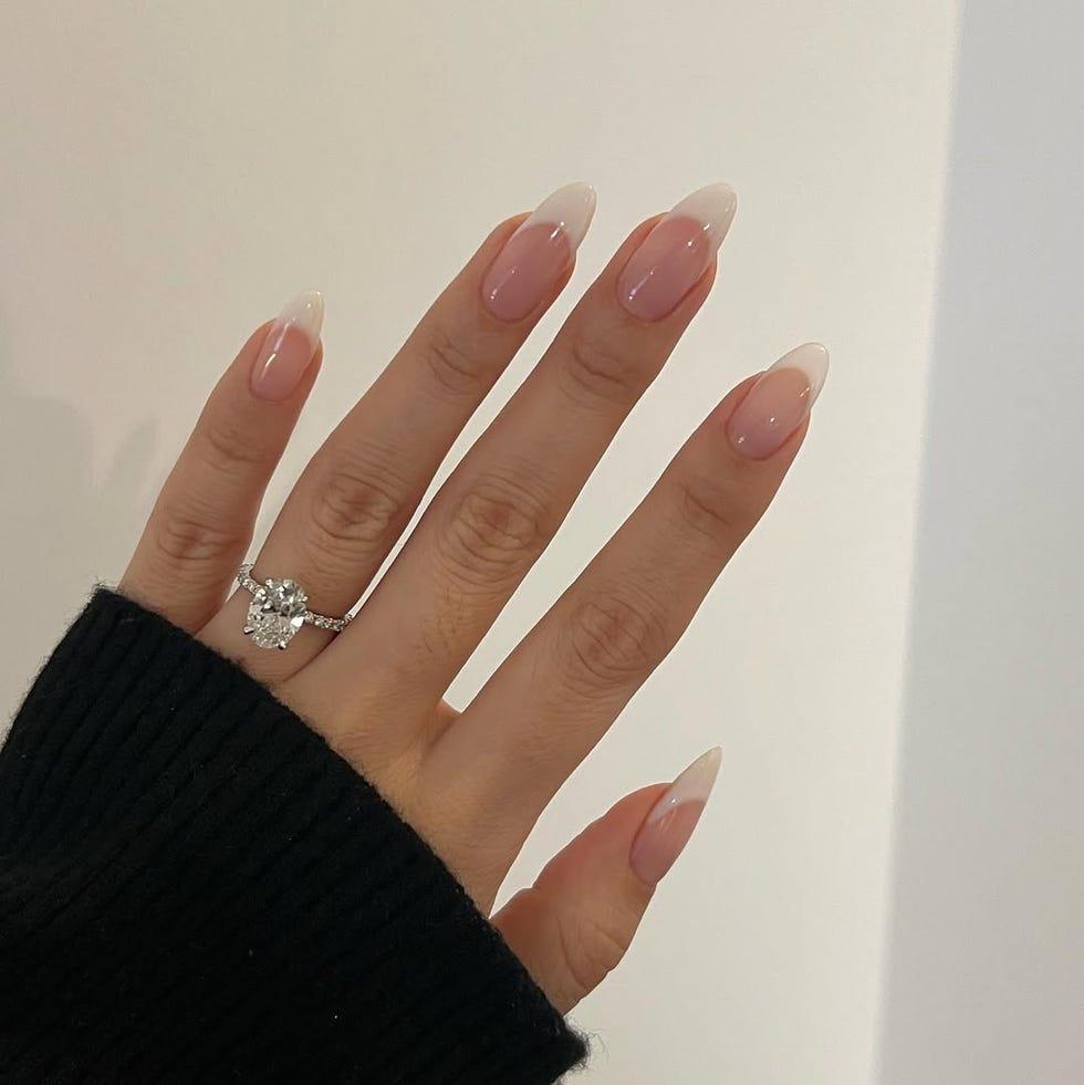 A hand with elegantly manicured nails and an engagement ring.