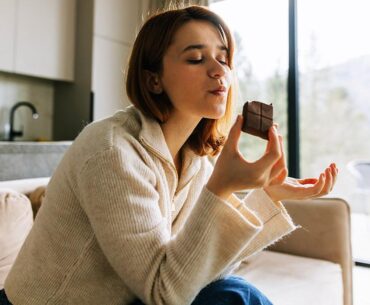 Woman enjoying chocolate on couch.