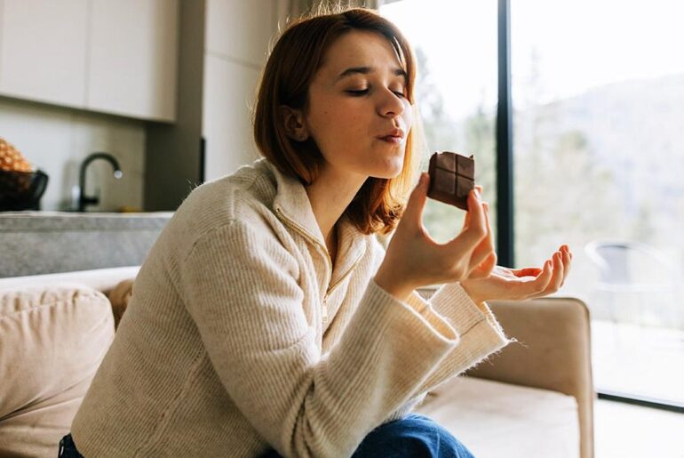 Woman enjoying chocolate on couch.