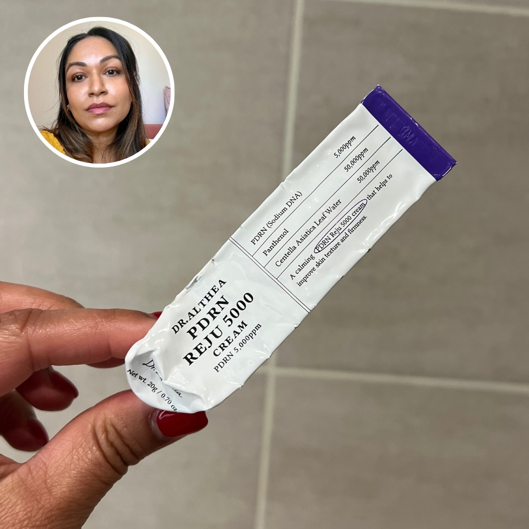 Hand holding an empty tube of Dr Althea PDRN Reju 5000 Cream, with circular photo of Aleesha Badkar in top left corner