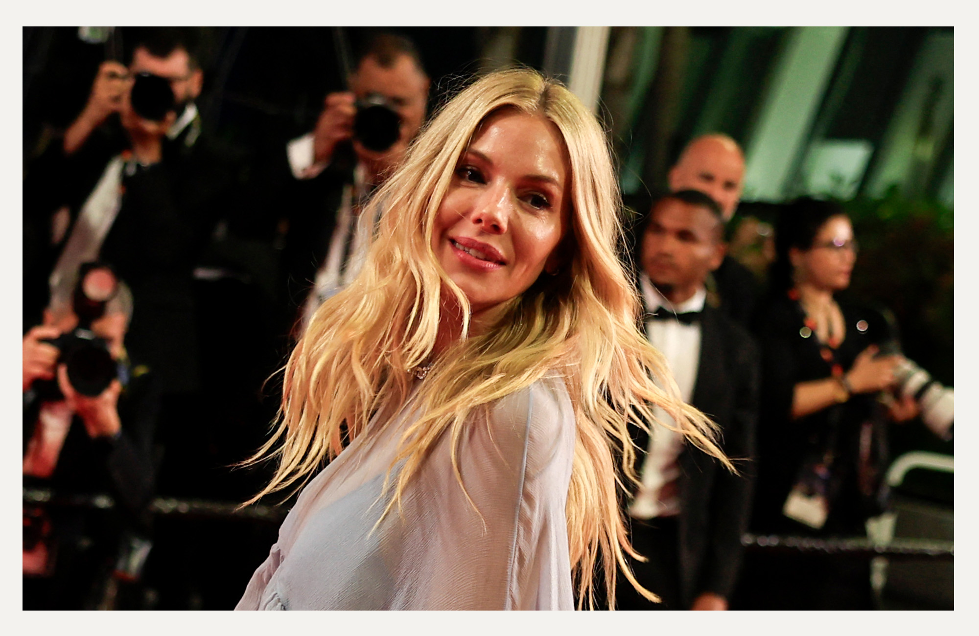 Sienna Miller walking a red carpet with lots of photographers