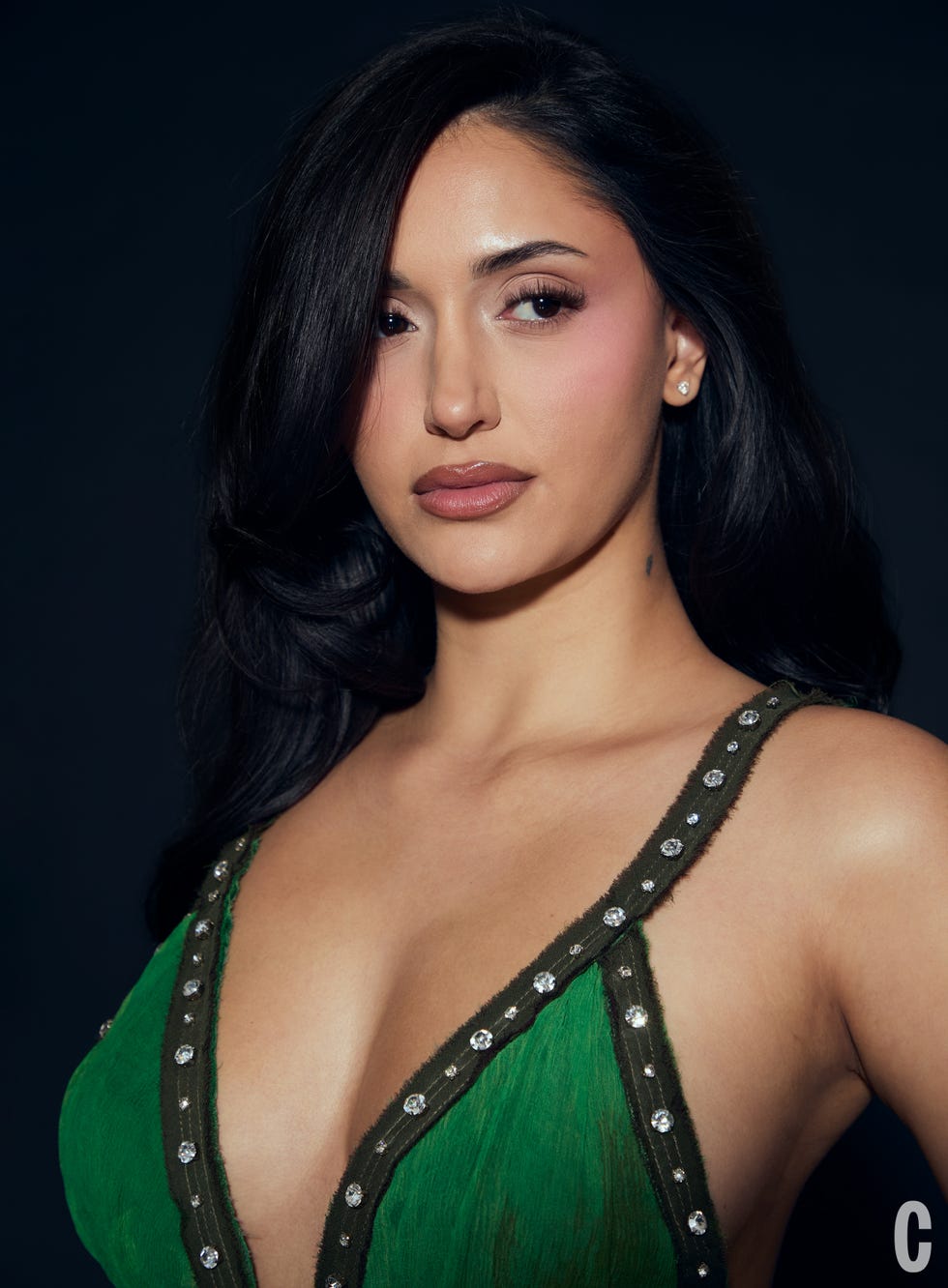 Close-up portrait of a woman in a green outfit with embellishments.