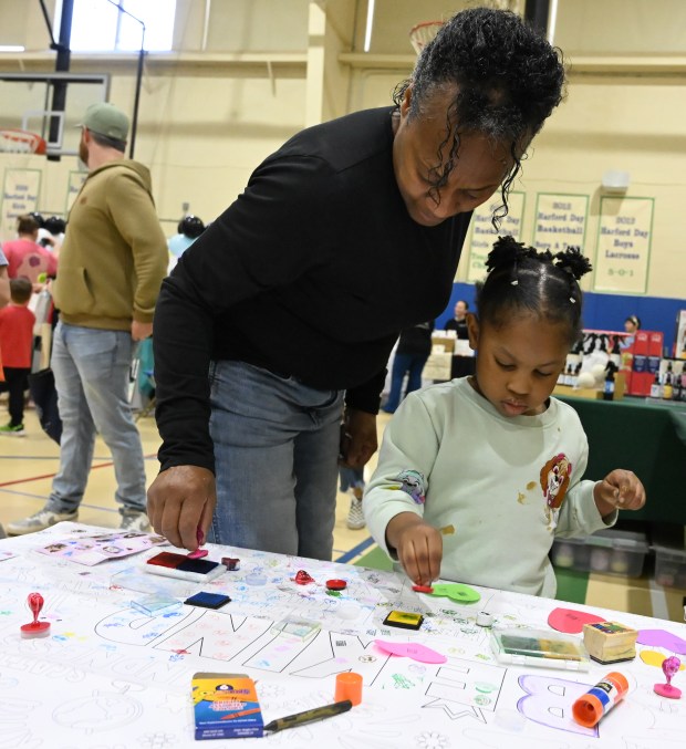 Dee Sills and her 3-year-old granddaughter Troi put their stamp on a growing community art piece at the Spring Into Wellness Fair, organized by Macaroni Kid Bel Air, at Harford Day School on Saturday. (Brian Krista/Staff)
