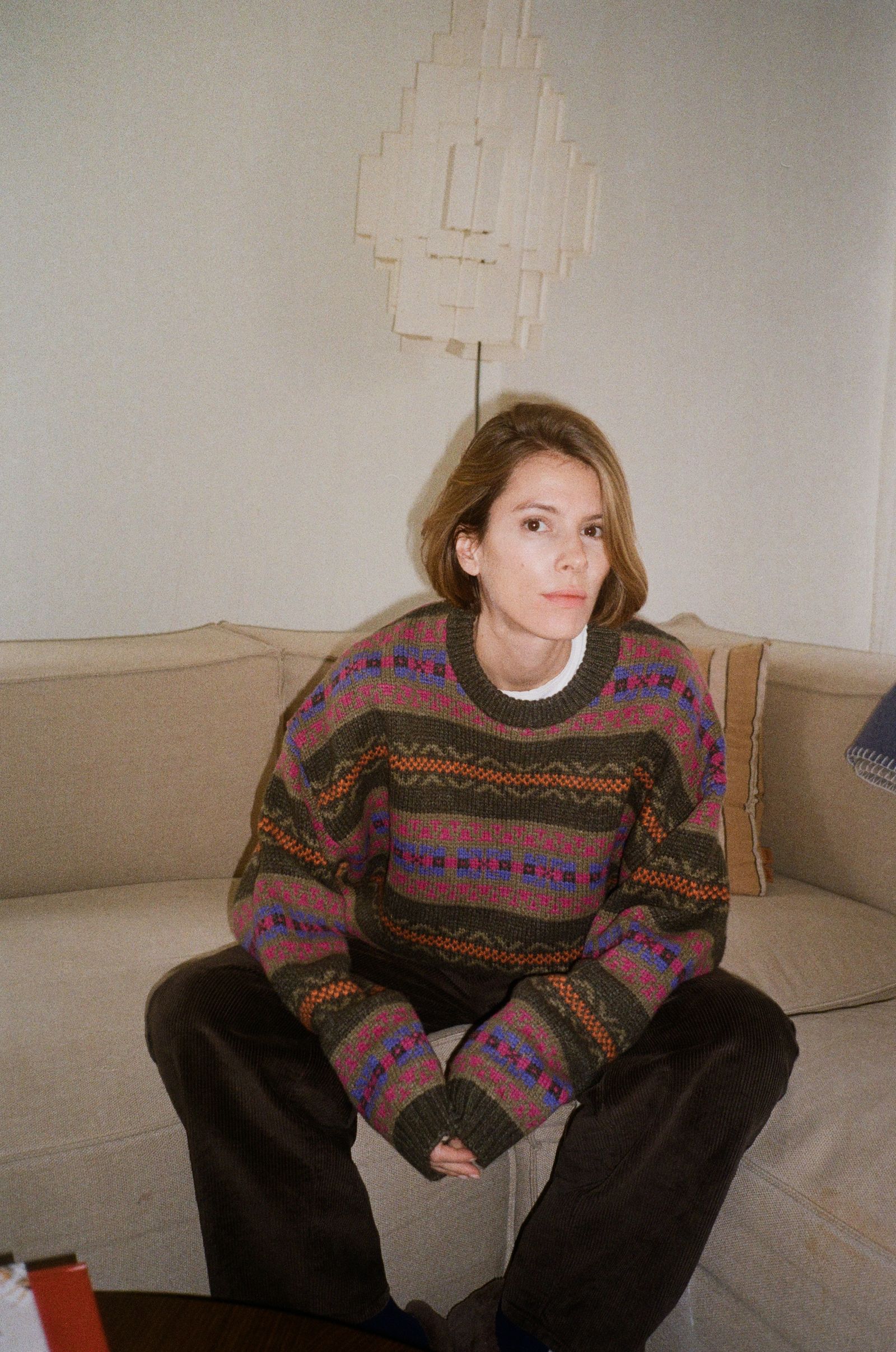 Image may contain Clothing Knitwear Sweater Lamp Couch Furniture Face Head Person Photography and Portrait