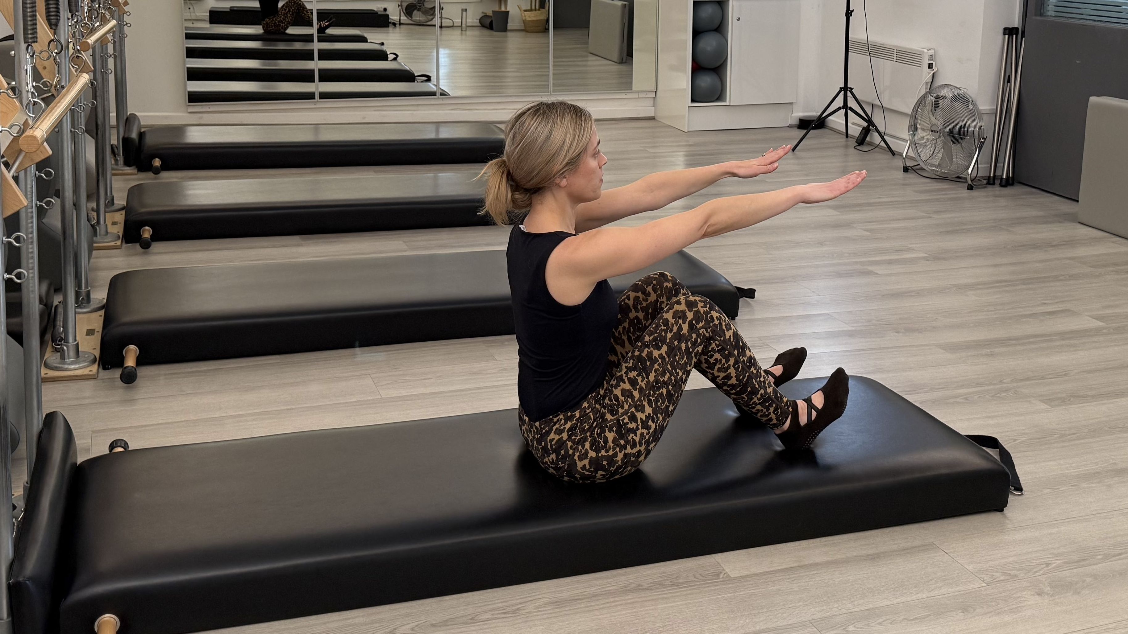 Woman demonstrating a Pilates movement in a studio setting