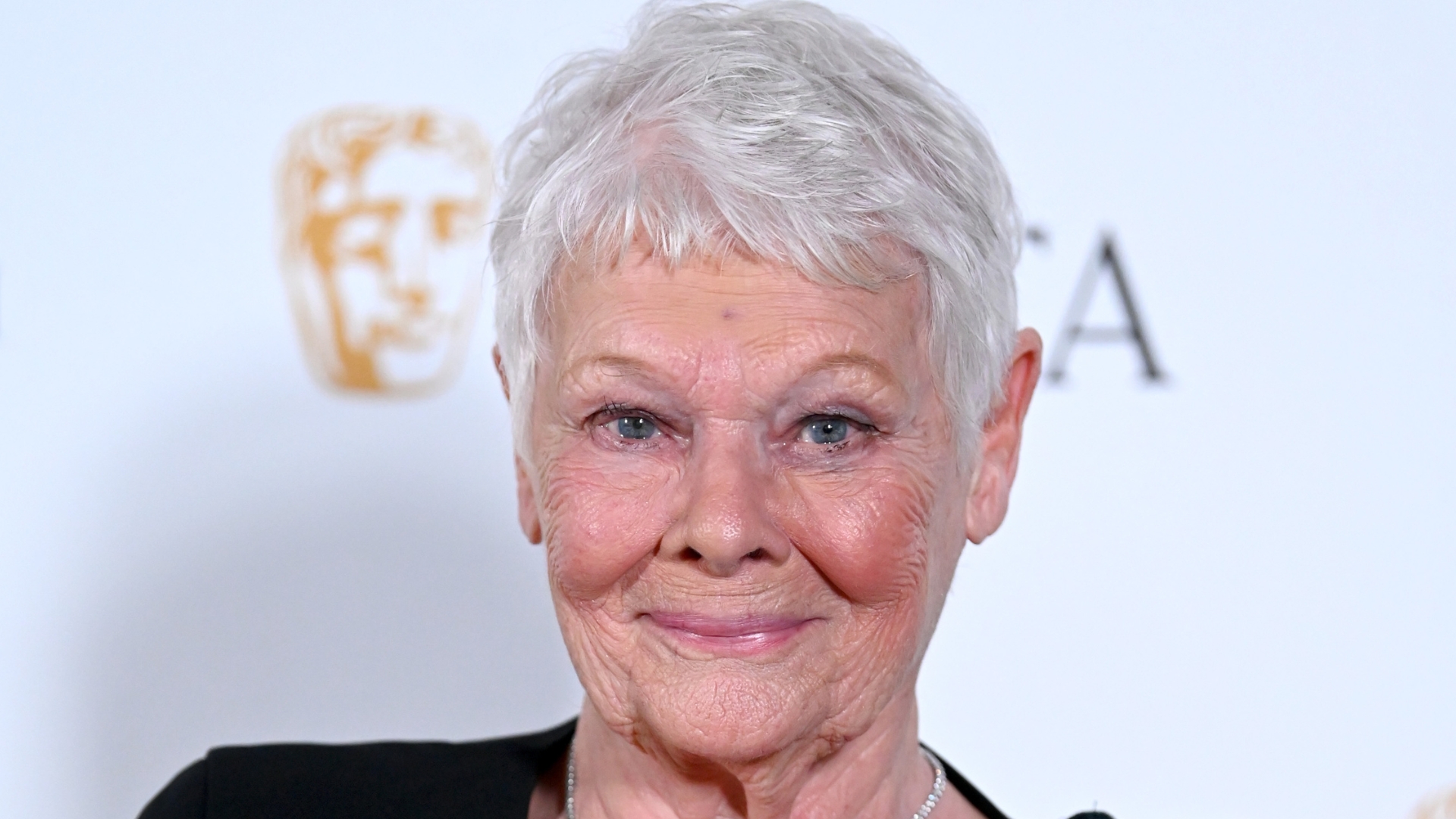 Image of Judi Dench smiling with silver pixie cut