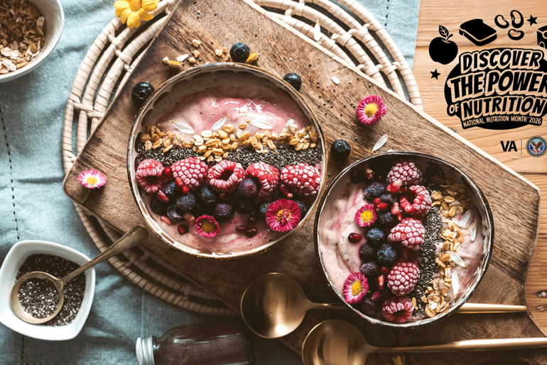 Two smoothie bowls topped with raspberries, blueberries, granola, and flowers sit on a wooden board. Text reads "Discover the Power of Nutrition."