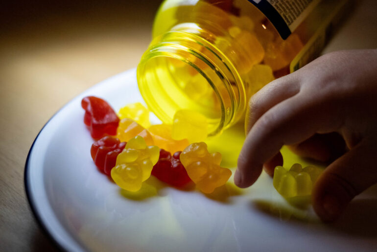 A child takes a children's vitamin bear from a plate.