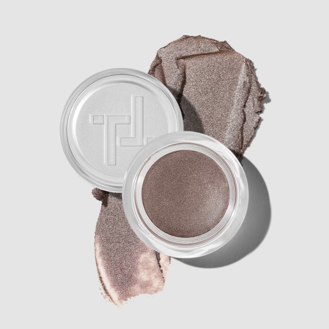 A product shot of the Trinny Eye2Eye cream eyeshadow in a metallic mole-brown colour, on a grey background