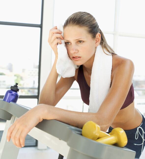 Close-up of a young woman wiping her face with a towel after a workout
