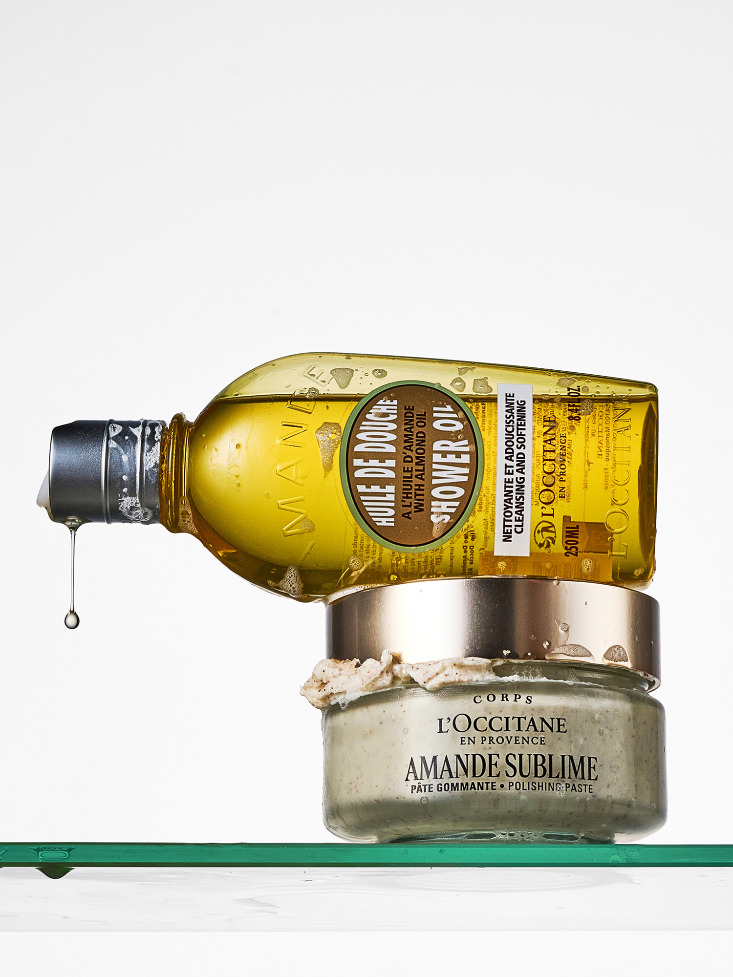 A picture of the L'Occitane shower oil and body scrub on a shower shelf