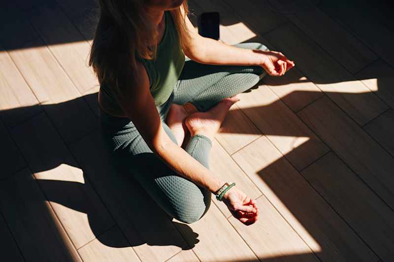 Woman meditating in sunlight at home
