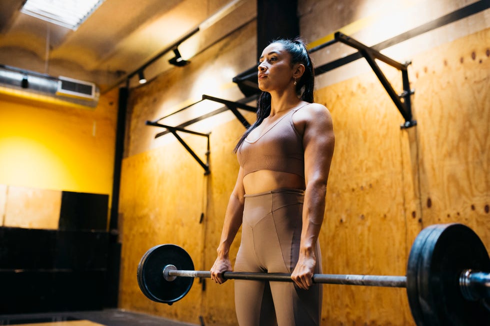 Woman lifting bar bell in gym young female athlete lifting bar bell in gym