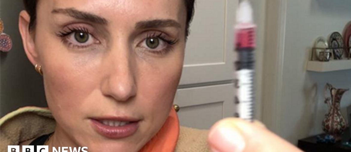 Katie, a woman with brown hair in a ponytail is holding up a syringe and injecting the peptide GHK-Cu into her bum cheek