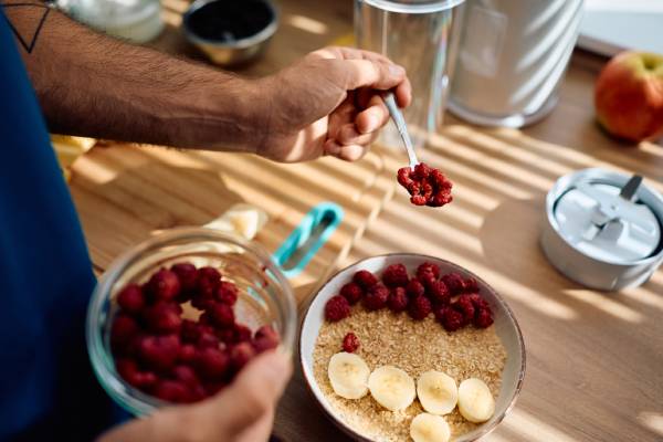 person adding berries, potentially from BerryWorld, to their breakfast