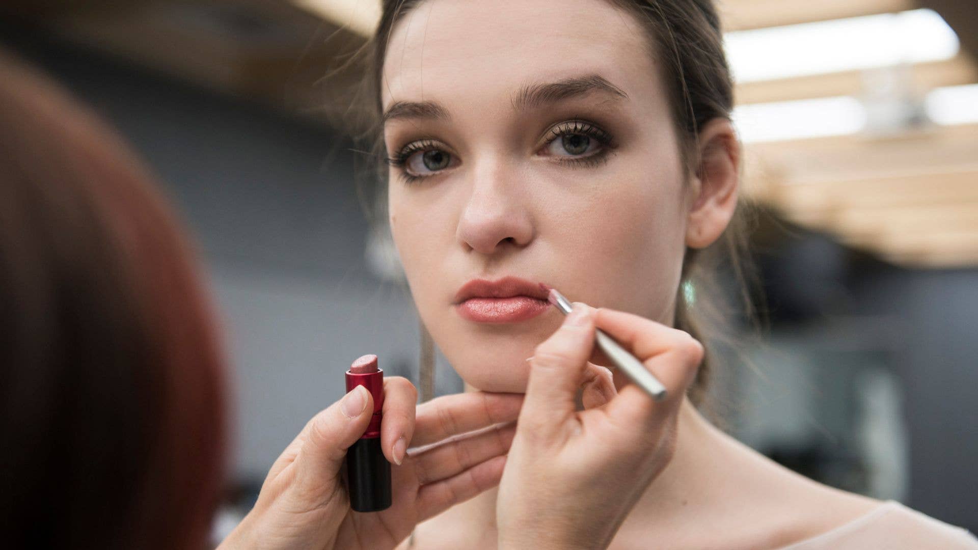 A model having her lipstick applied backstage 