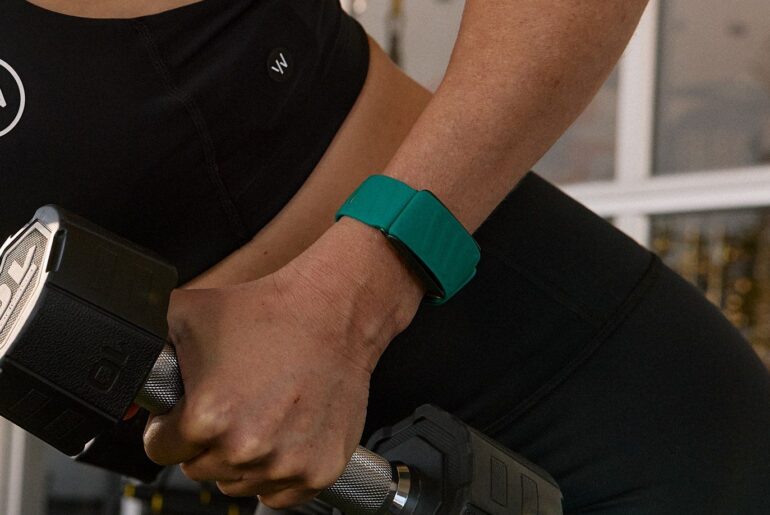 Woman lifting dumbbell while wearing Whoop device on wrist