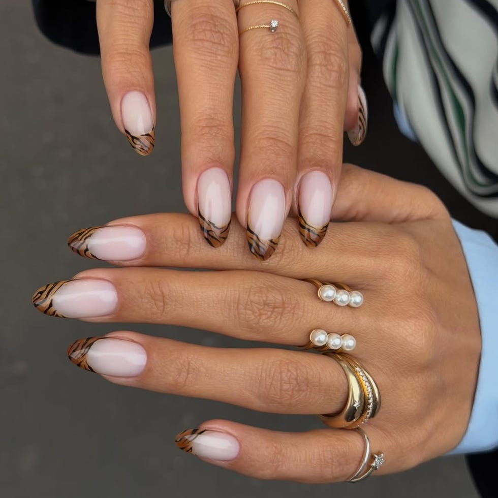 Manicured hands with nail art and multiple rings.