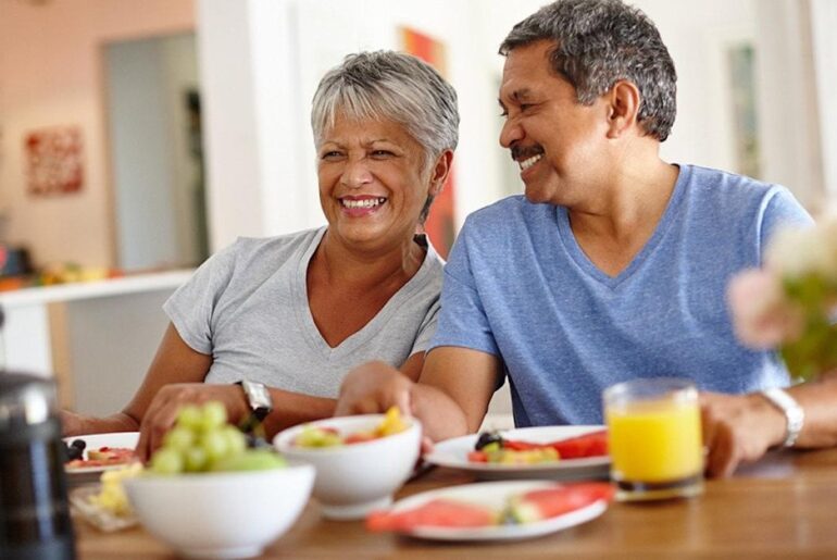 A retired senior couple happily having breakfast at home. - PeopleImages // Shutterstock