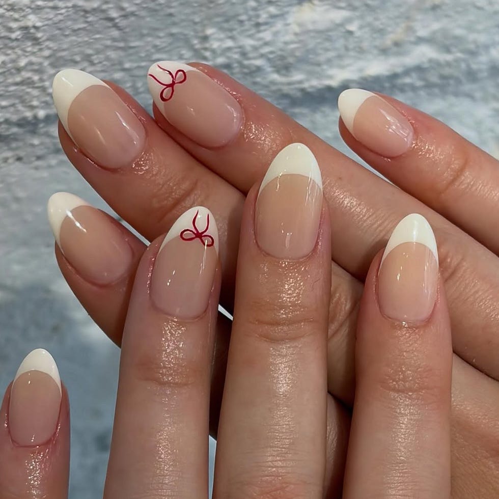 Nail art featuring a French manicure with red bow designs.