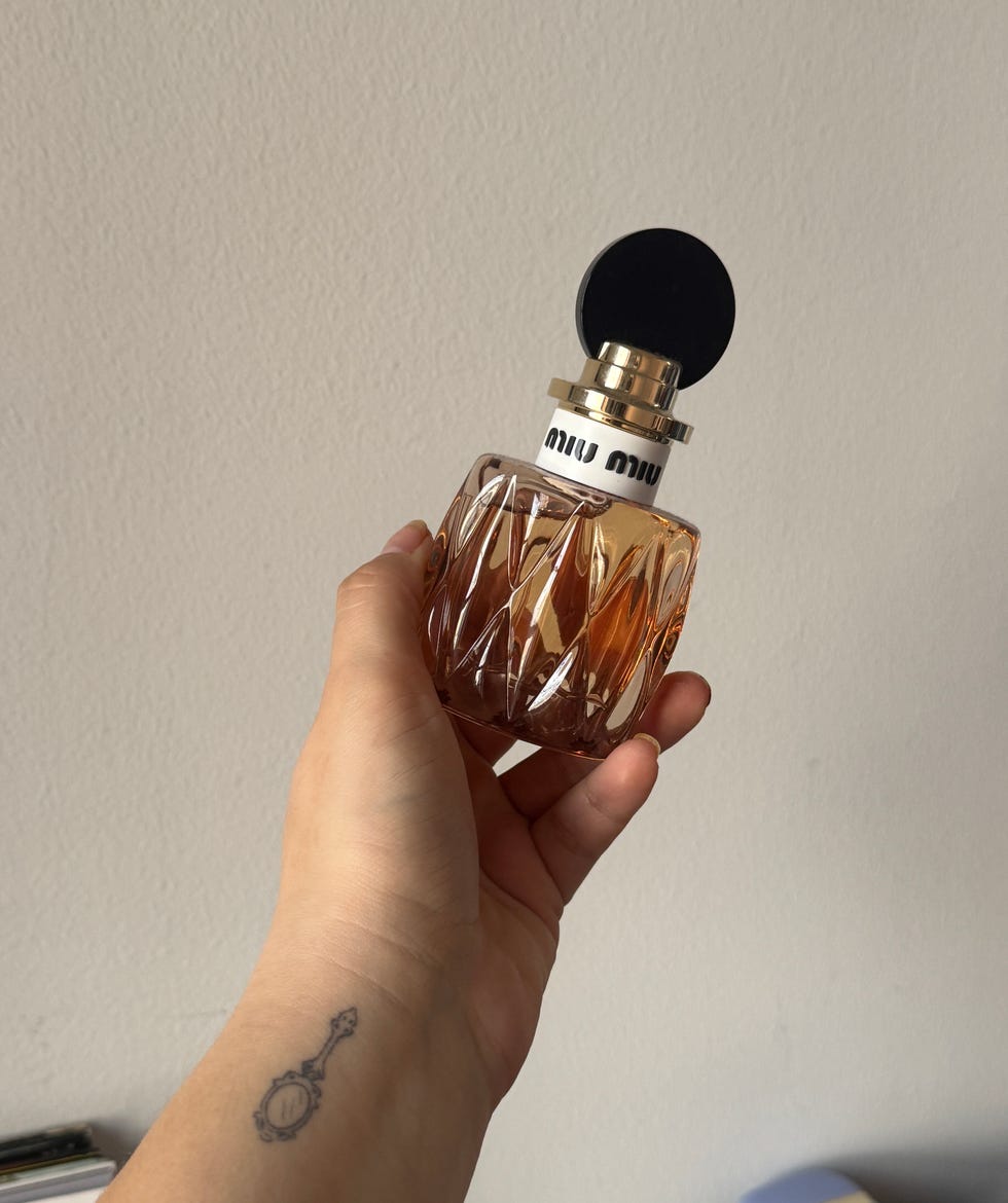 Hand holding a perfume bottle against a plain background. Hand holding a perfume bottle against a plain background.