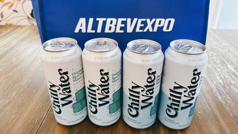 Chilly Water cans on wooden table in front of a blue bag from the Alt Bev Expo