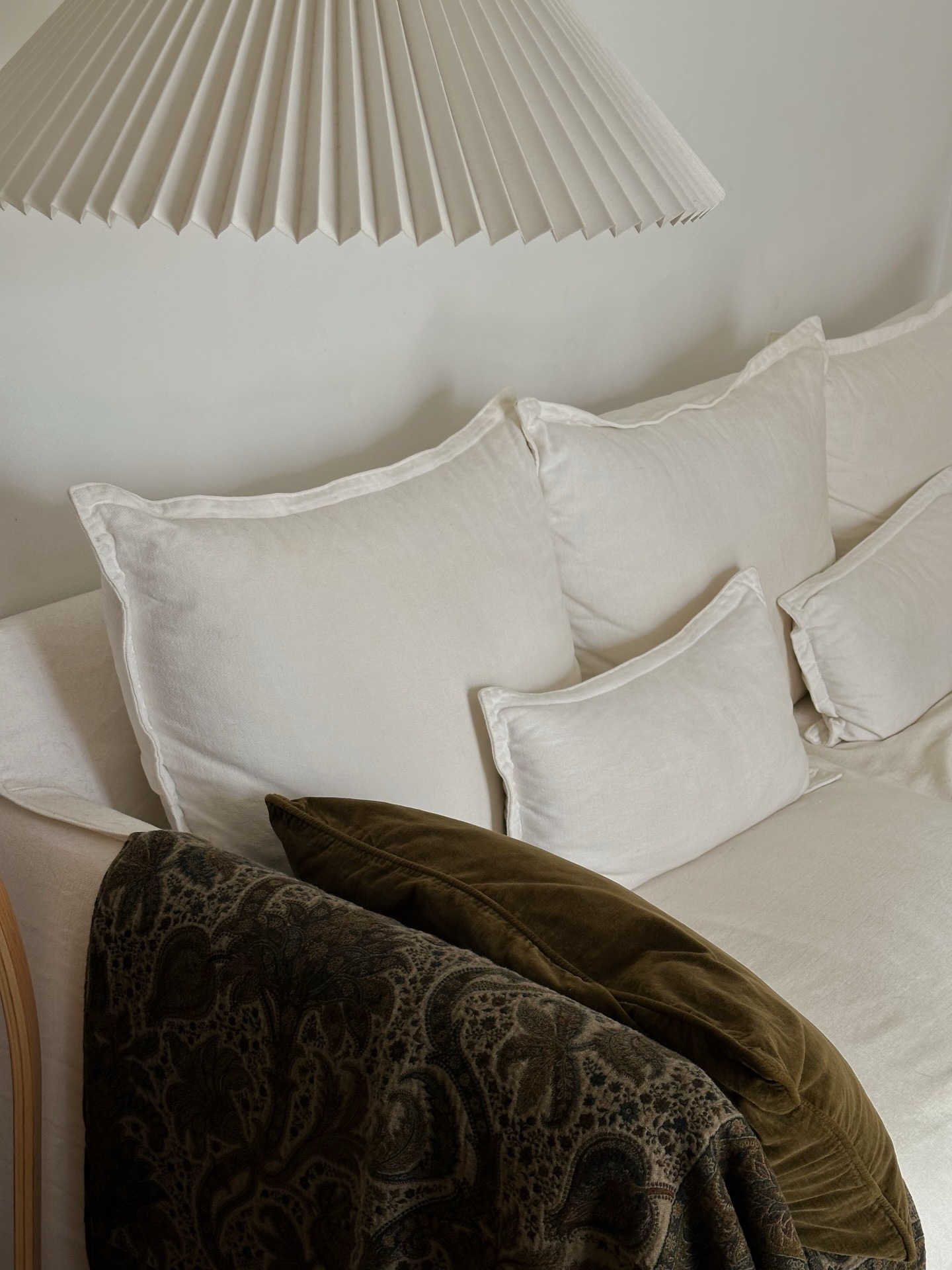 A chic cream sofa with a dark green throw and pillow