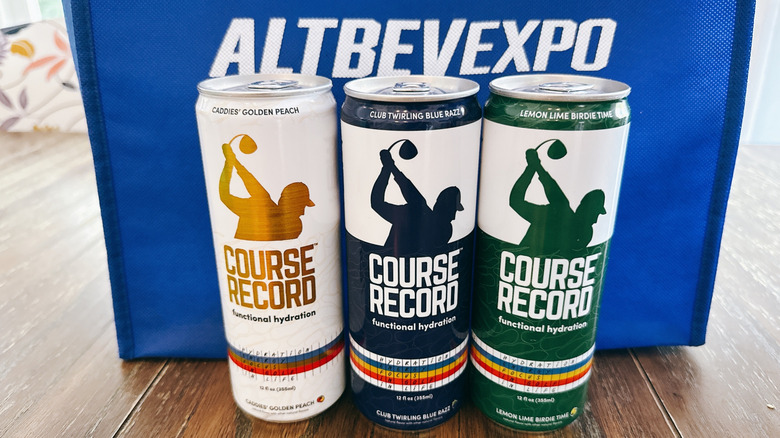 Course Record cans on wooden table in front of a blue bag from the Alt Bev Expo