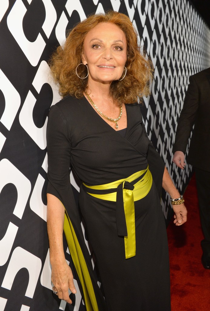 Designer Diane Von Furstenberg poses in a black dress with a chartreuse sash and a black and white patterned backdrop.