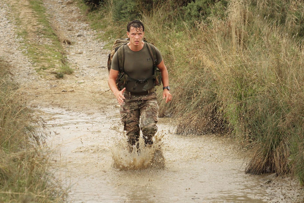 person running through a puddle on a gravel path
