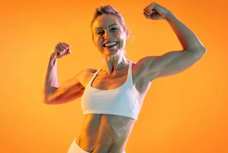 A woman flexing her biceps and smiling.
