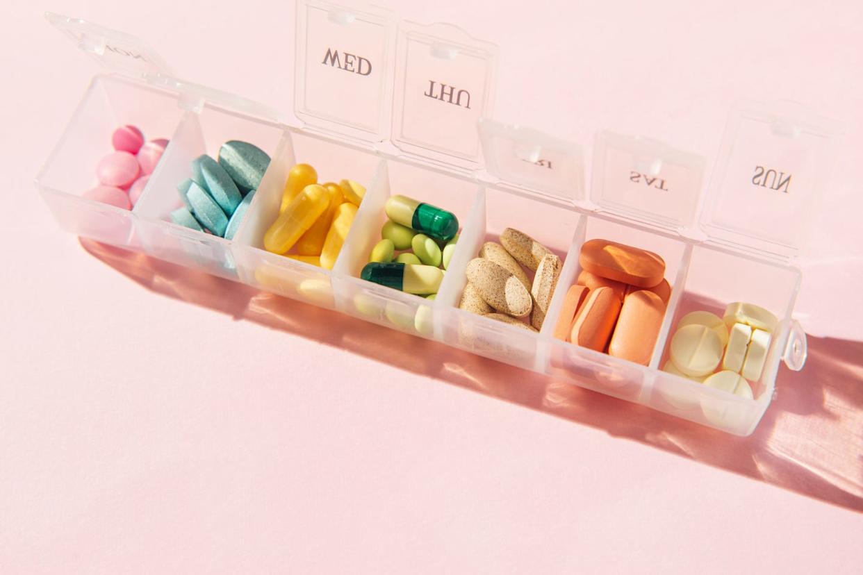Box for pills and capsules on pink background. Pills organizer.