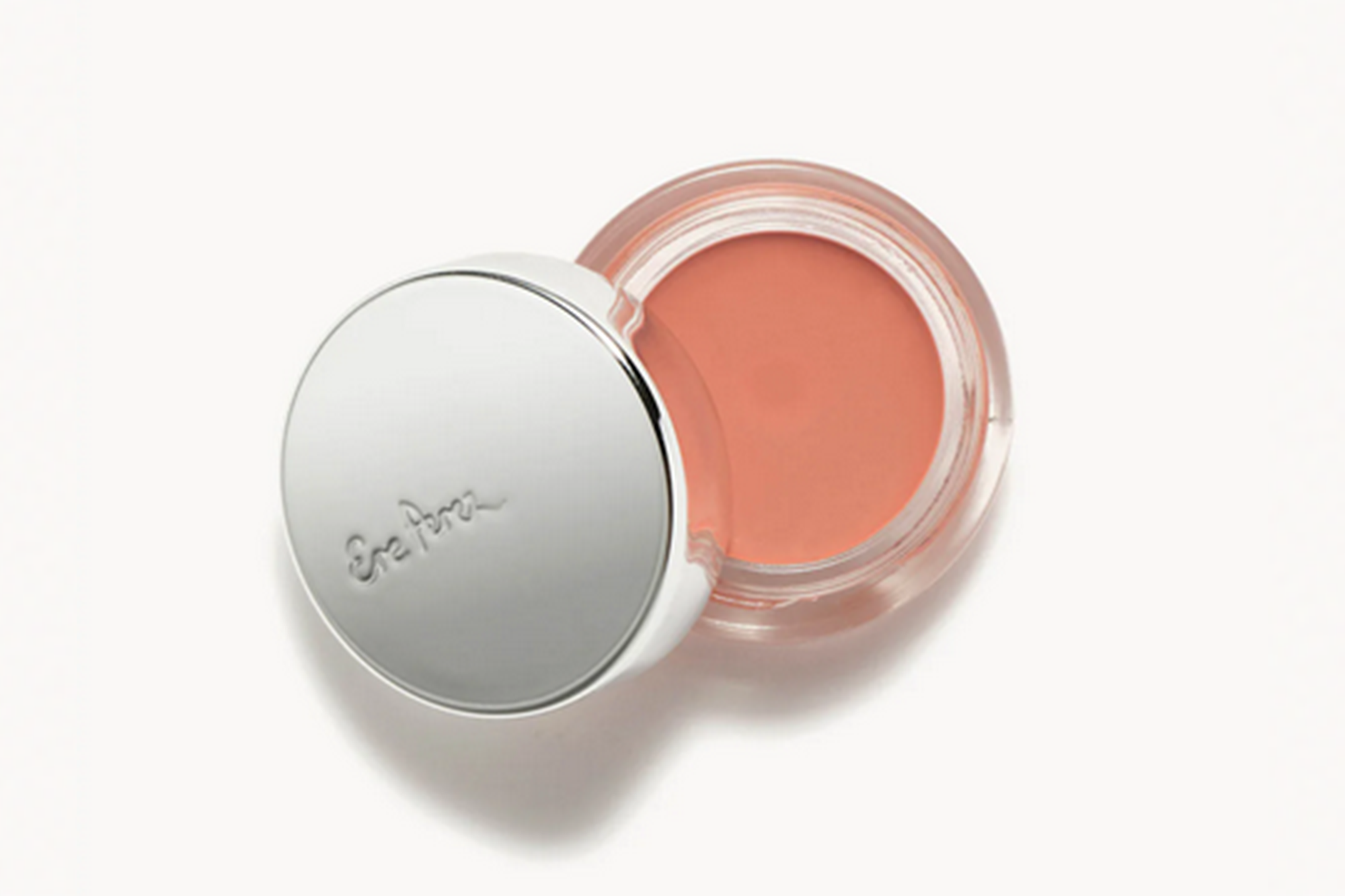 Open pot of peach-colored cream blush with a silver lid that reads "Ere Perez".