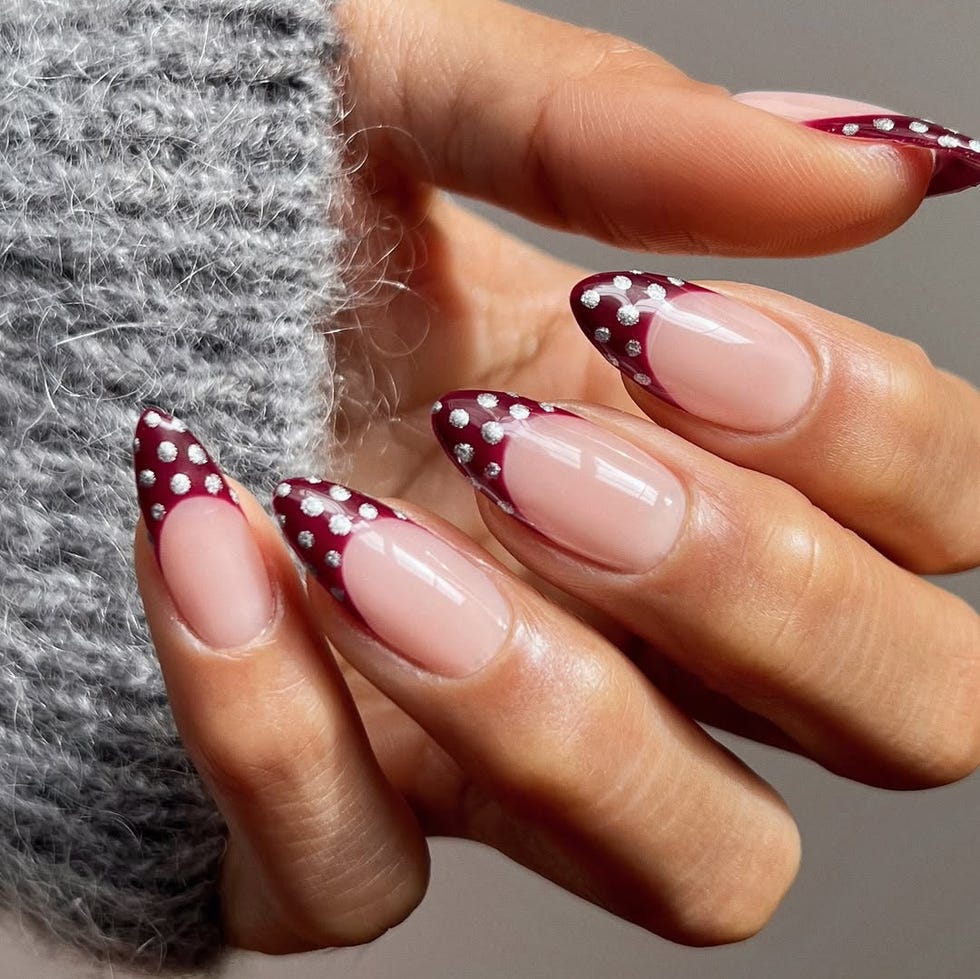 Stylish manicure featuring burgundy tips and embellishments.