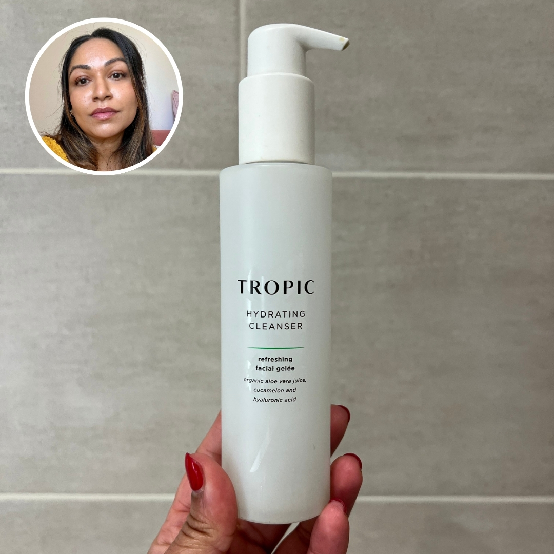 Hand holding an empty bottle of Tropic Skincare Hydrating Cleanser Refreshing Facial Gelée, with circular photo of Aleesha Badkar in top left corner