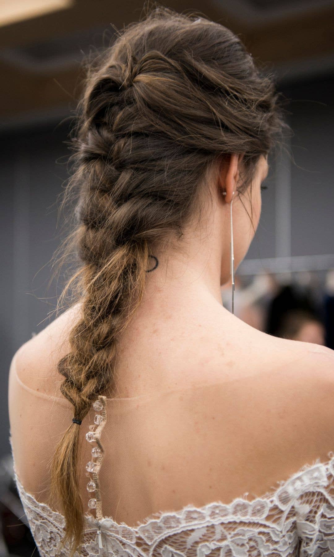 A model backstage at a bridal show with a long French plait