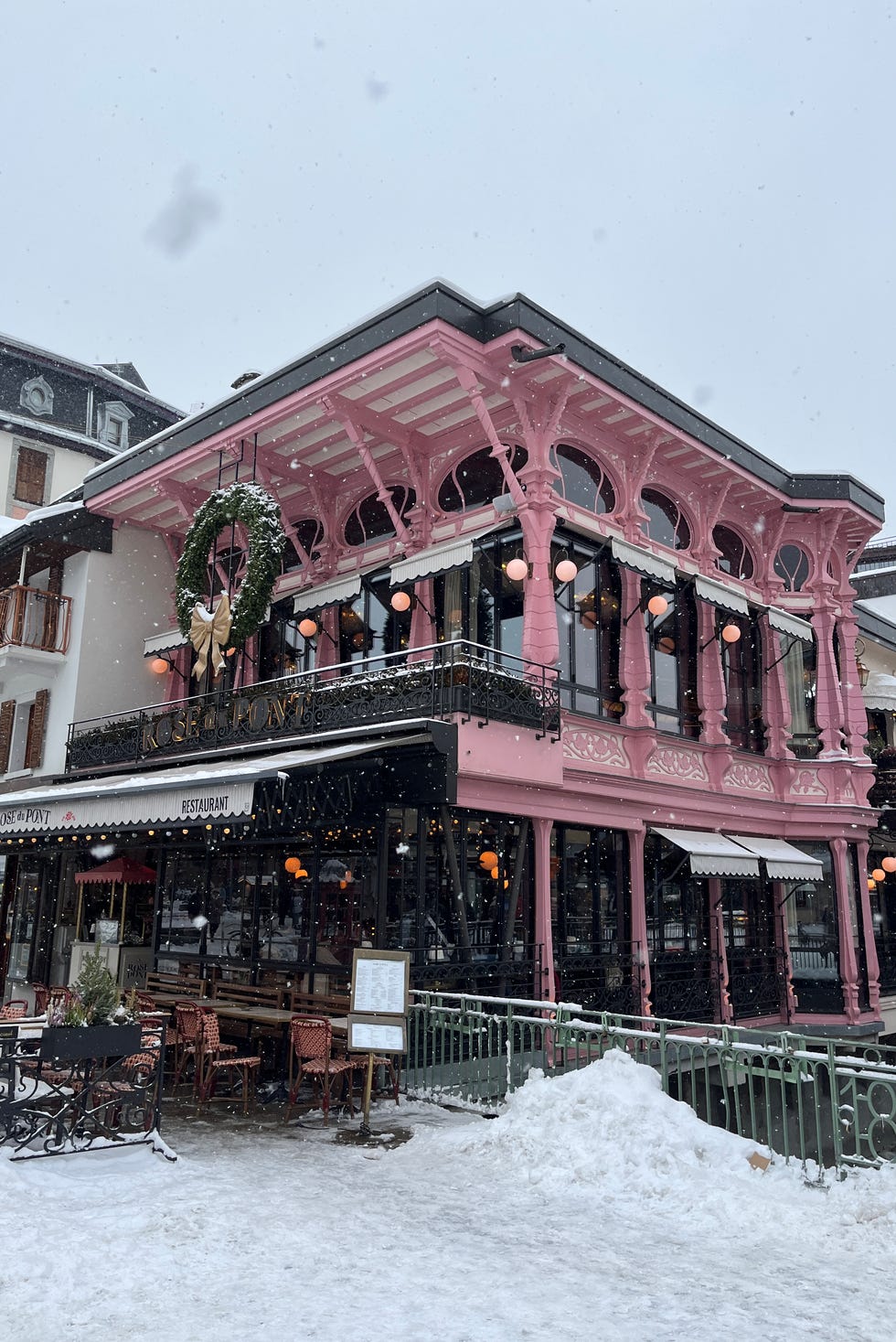 snowy scene depicting a pink building with outdoor dining girl powder retreat review