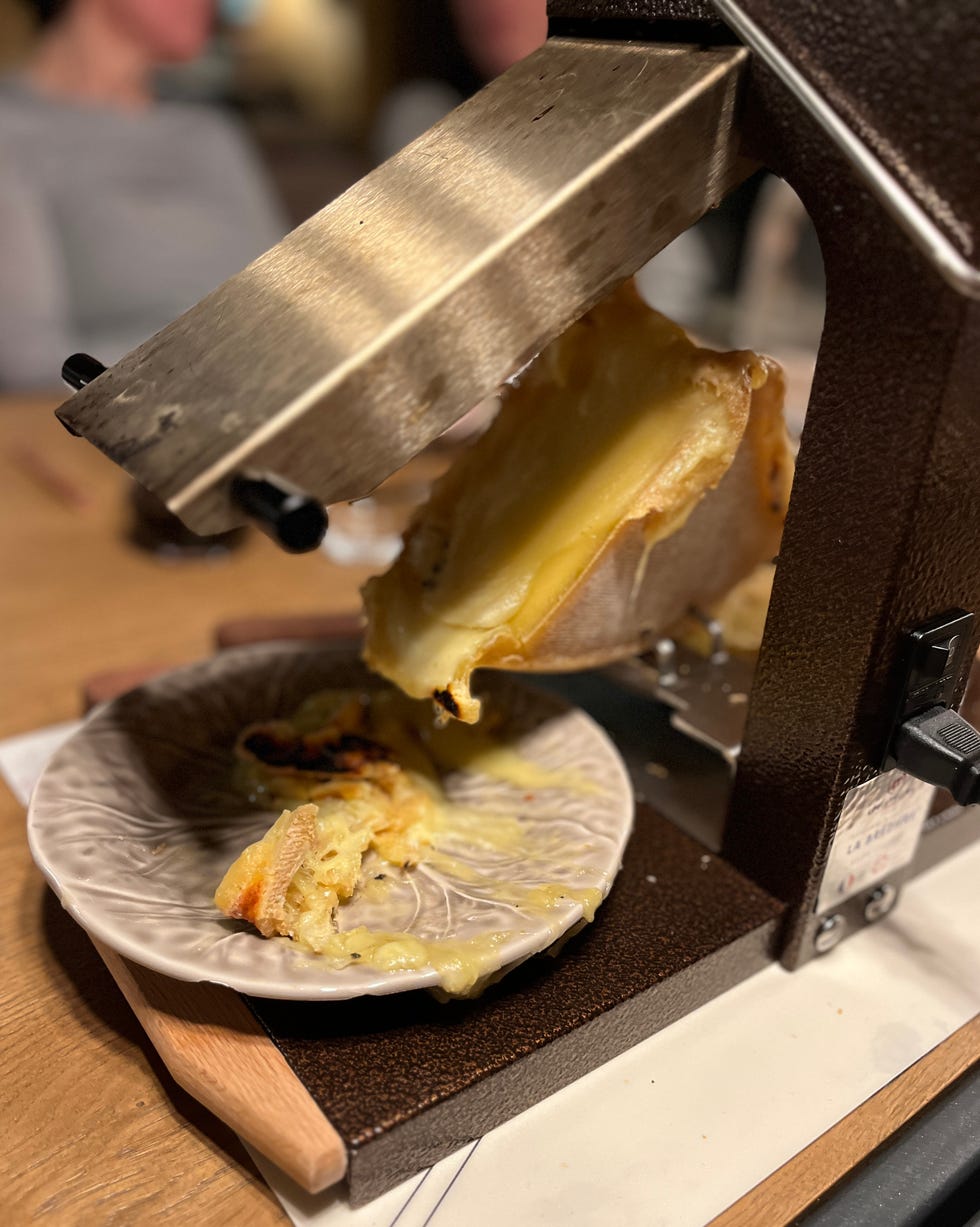 cheese being melted and served from a raclette machine onto a plate girl powder retreat review