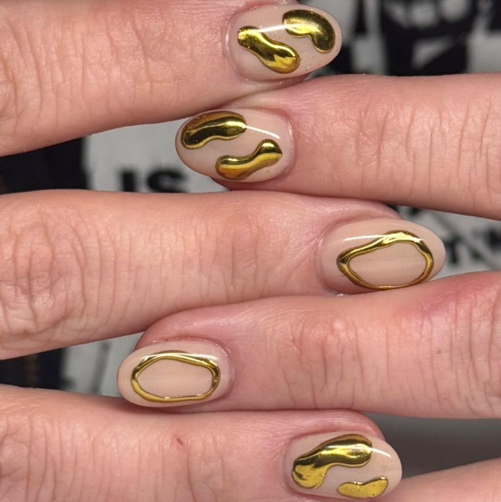 nail art featuring abstract gold designs on a nude background