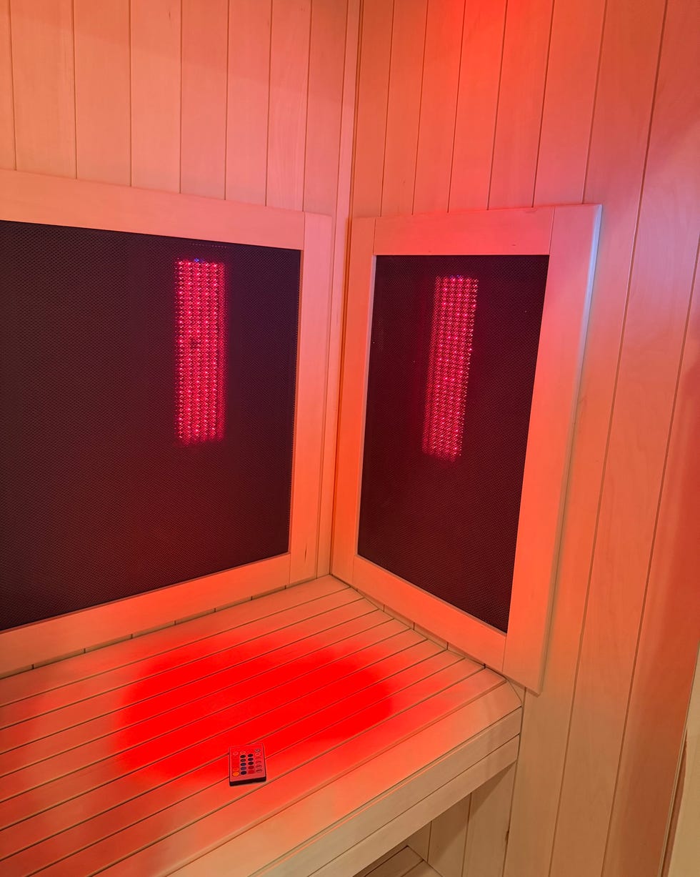 interior of a sauna featuring red lighting and a control panel