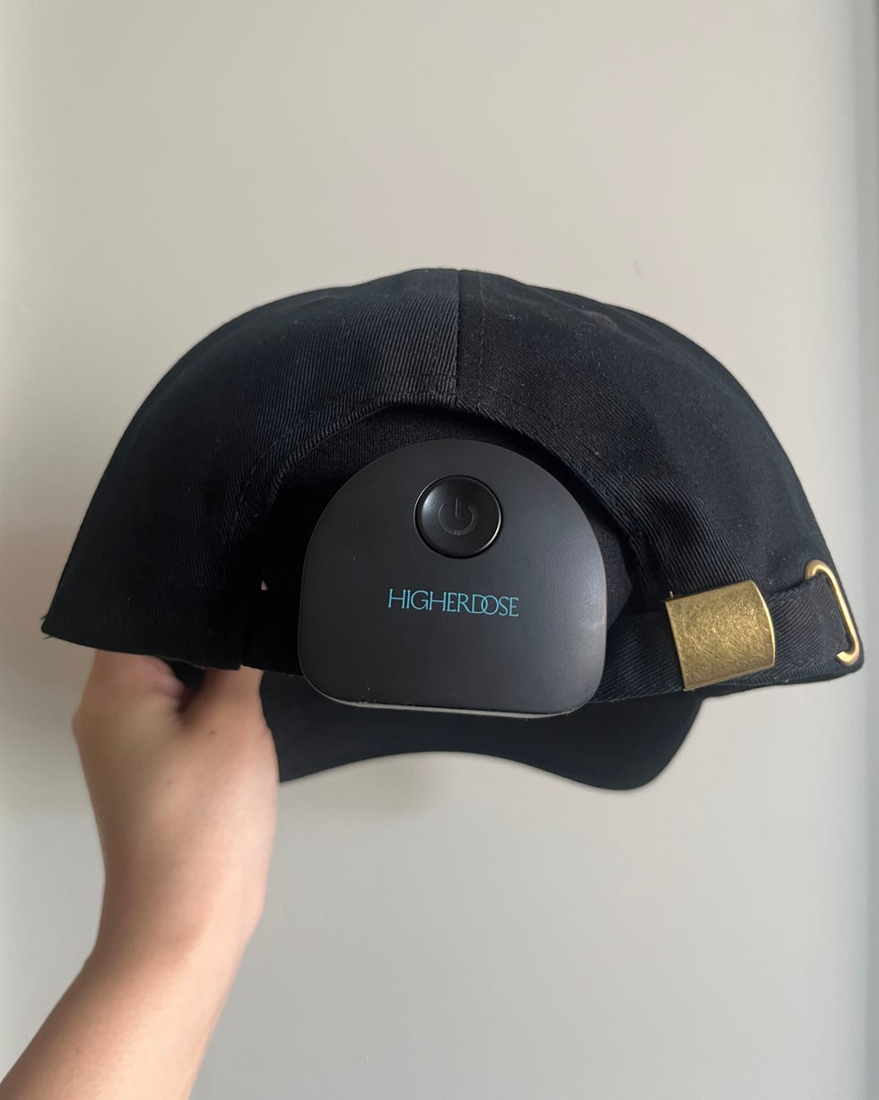 black cap being held with a device attached to its underside