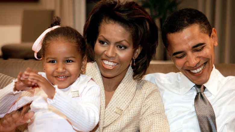 Sasha, Michelle, and Barak Obama smile next to eachother