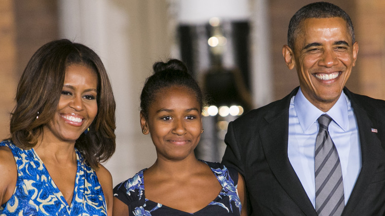 Michelle, Sasha, and Barack Obama smile wearing blue