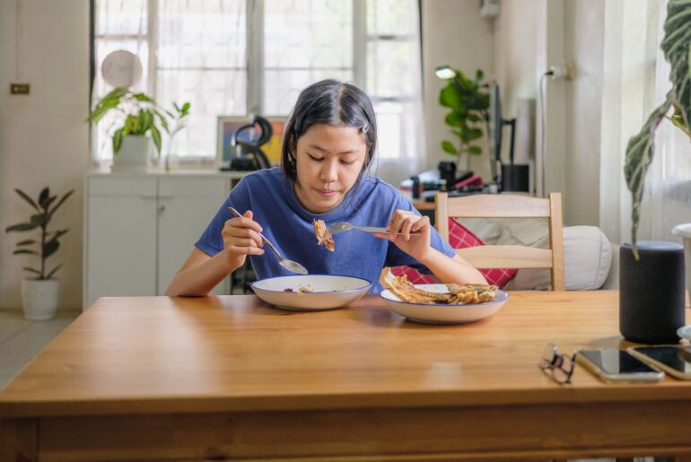 Woman sitting at kitchen table eating