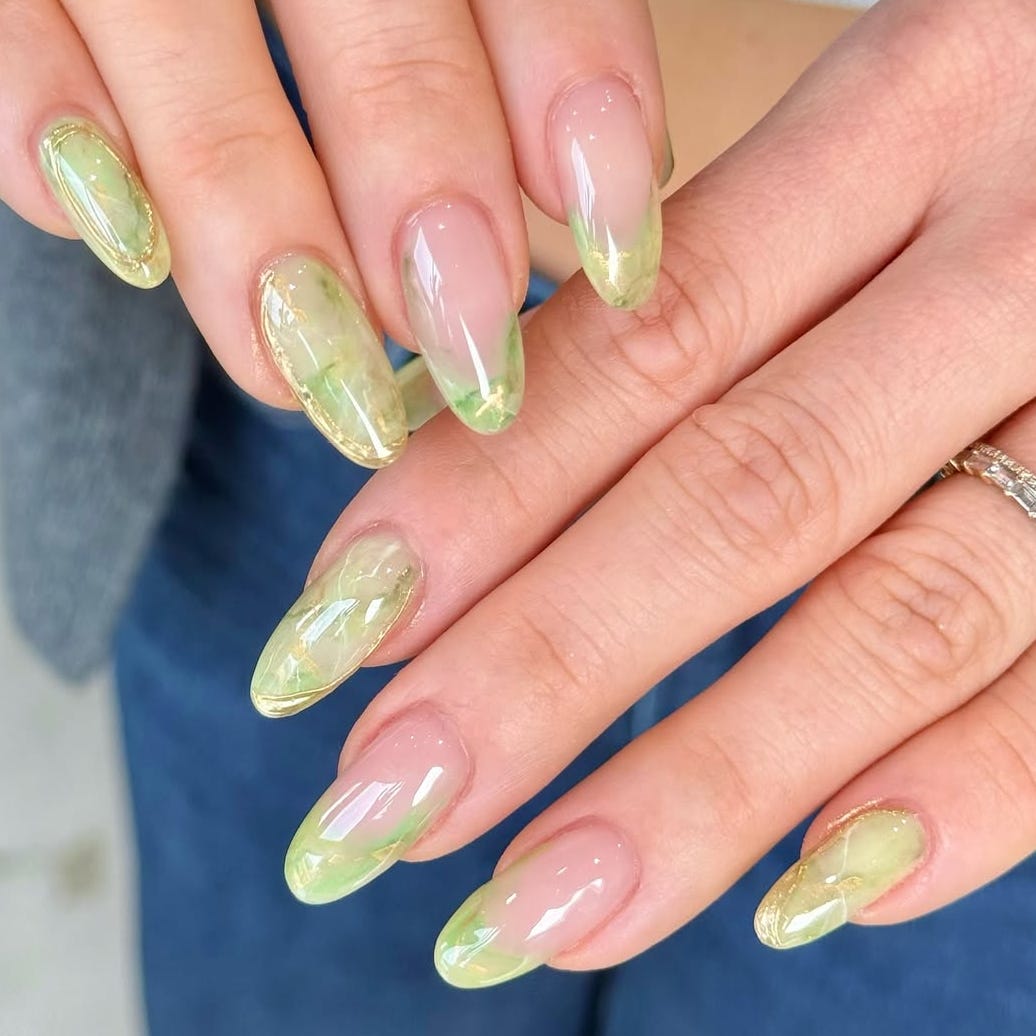 a stylish manicure featuring elongated nails with a green and clear gradient design