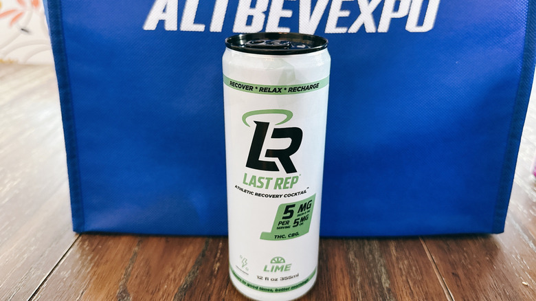 Last Rep can on wooden table in front of a blue bag from the Alt Bev Expo